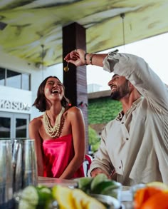 a man standing next to a woman in front of a table with fruit on it