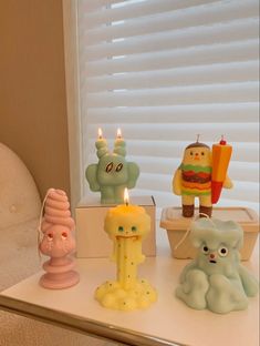 three candles sitting on top of a white table next to a window with blind blinds