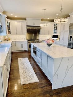 a large kitchen with white cabinets and marble counter tops, an island in the middle