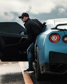 a man sitting on the hood of a blue sports car