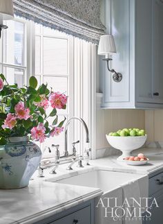 a bowl of flowers sitting on top of a kitchen counter next to a sink and window