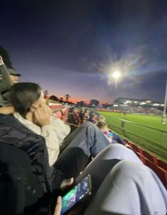 people are sitting in the stands at a baseball game and one person is on his cell phone