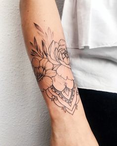 a woman's arm with a flower tattoo on the left side of her arm