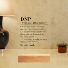 a glass plaque with the words dndp on it sitting next to a lamp