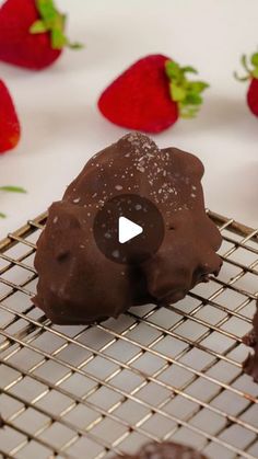 chocolate covered doughnuts on a cooling rack with strawberries in the background