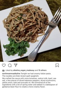 a white plate topped with pasta and greens next to a fork on top of a table