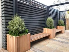 two wooden benches sitting next to each other on a brick floored patio with black slatted walls