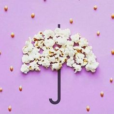 popcorn and an umbrella on a purple background with peanuts scattered around it, as if for the movie