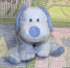 a blue dog stuffed animal sitting on top of a bed next to a baby crib