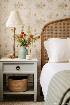 a bedroom with flowers on the wall next to a bed and nightstand in front of it