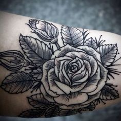 a black and white rose tattoo on the right arm, with leaves around it's edges