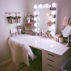 a white vanity with lights on it and a fur coat hanging from the top shelf