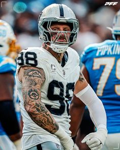 a close up of a football player with tattoos on his arm and chest, wearing a white uniform