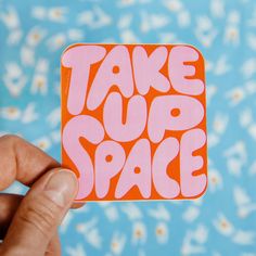 someone holding up a sticker with the words take off space in pink and orange