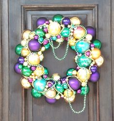 a wreath made out of beads and pearls on a wooden door with the words mardi gras written below it