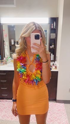 a woman taking a selfie in a bathroom mirror wearing an orange dress with colorful flowers on it