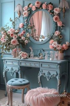 a blue vanity with pink flowers on it and a round mirror above the dresser, along with a stool