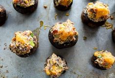 an overhead view of stuffed mushrooms on a baking sheet with cheese and other toppings