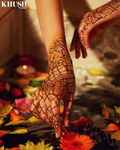 a woman's hands with hennap and flowers on the ground in front of her