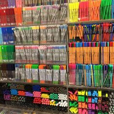 many different colored pens and pencils are on display in a store with clear bins