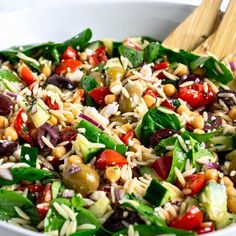 a salad in a white bowl with wooden spoons on the side, ready to be eaten