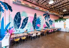 the interior of a restaurant with colorful murals on the wall and tables set up in front of them