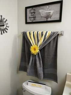 a towel hanging on the side of a toilet in a bathroom with a yellow flower