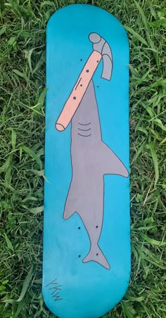 a skateboard with a drawing of a shark holding a hammer on it's back