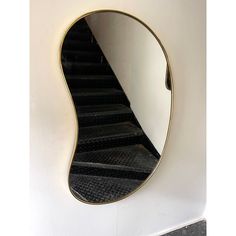 a mirror hanging on the side of a wall next to a stair case in a room