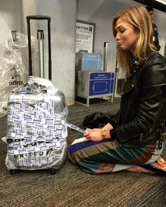 a woman is sitting on the floor with her luggage in front of her at an airport