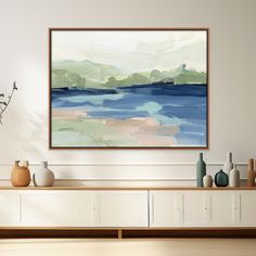 an abstract painting hangs on the wall above a table with vases and other items