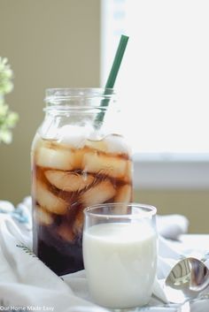 a jar filled with liquid sitting on top of a table next to a glass full of milk