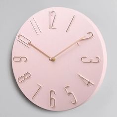 a pink clock with numbers on the face and hands is shown in front of a gray background