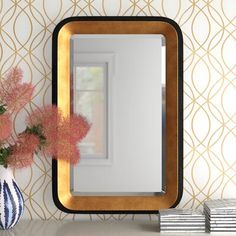 a mirror sitting on top of a table next to a vase with flowers