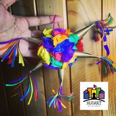 a hand holding a bouquet of multicolored flowers on top of a wooden wall