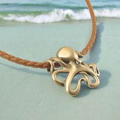 an octopus necklace is on the beach with waves in the background and blue water behind it