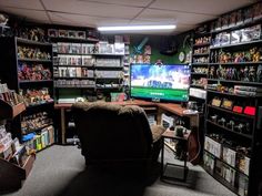 a room filled with lots of toys and games on shelves next to a chair in front of a tv