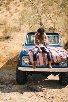 a woman sitting on top of a blue truck