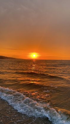 the sun is setting over the water at the beach