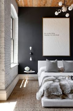 a bedroom with black walls, white bedding and an art work on the wall