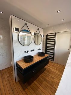 a bathroom with two sinks and mirrors on the wall next to a wooden counter top