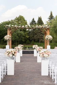 an outdoor ceremony with white chairs and flowers