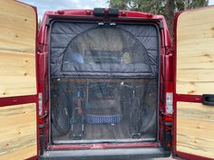 the back end of a red van with wood paneling and bike racks in it