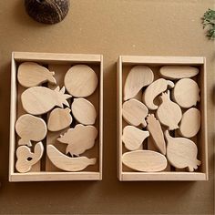 two boxes filled with wooden cutouts sitting on top of a table next to an acorn