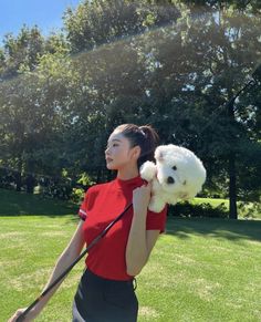 a woman in a red shirt holding a white dog