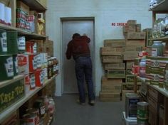 a man is standing in the door way of a storage room filled with boxes and cans