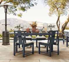 an outdoor dining table with chairs around it