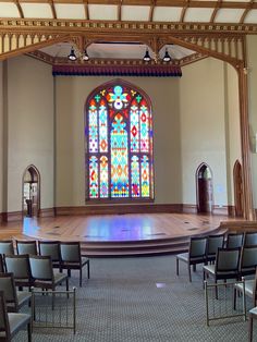 an empty church with stained glass windows and pews in the front row, on a carpeted floor