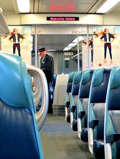 a man standing in the middle of an empty train car with blue seats on both sides