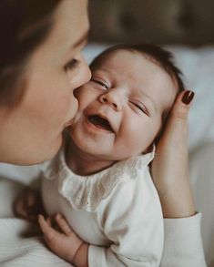 a woman kissing a baby on the cheek